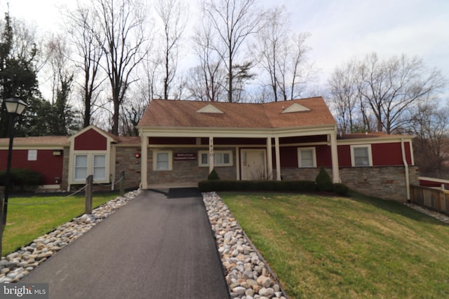 view of front of property with driveway, covered porch, stone siding, and a front lawn