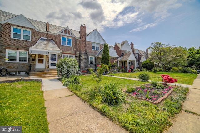 view of front of house featuring a chimney, stone siding, a high end roof, and a front lawn