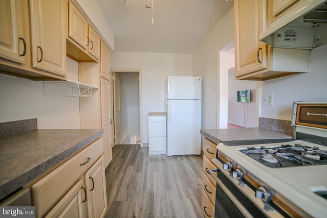 kitchen with wood finished floors, freestanding refrigerator, under cabinet range hood, gas range oven, and dark countertops