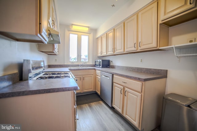 kitchen with a sink, dark wood-type flooring, light brown cabinets, dark countertops, and appliances with stainless steel finishes