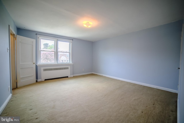 carpeted spare room with baseboards and radiator
