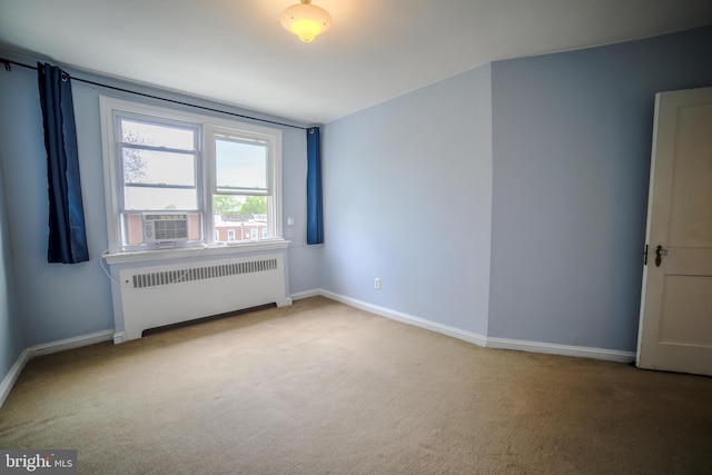 carpeted empty room featuring baseboards, cooling unit, and radiator heating unit
