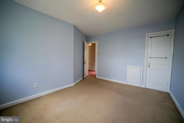 carpeted empty room featuring baseboards