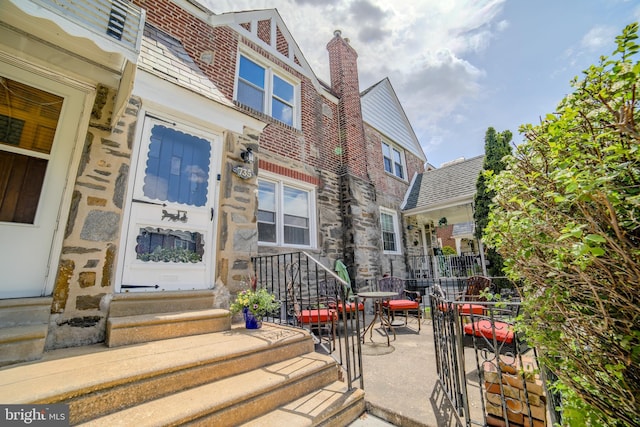 view of exterior entry featuring stone siding, a chimney, and brick siding