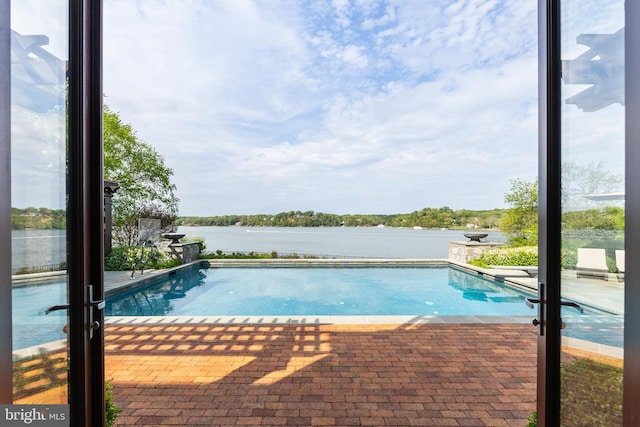 outdoor pool featuring a patio and a water view