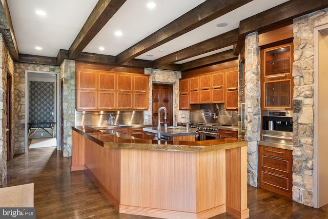 kitchen with dark wood-style flooring, appliances with stainless steel finishes, a sink, stainless steel counters, and tasteful backsplash