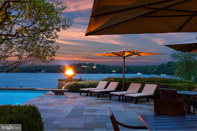 view of patio featuring outdoor dining area, a water view, and an outdoor pool