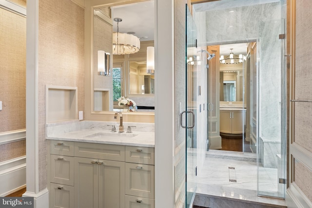 full bathroom with vanity, a shower stall, and a chandelier