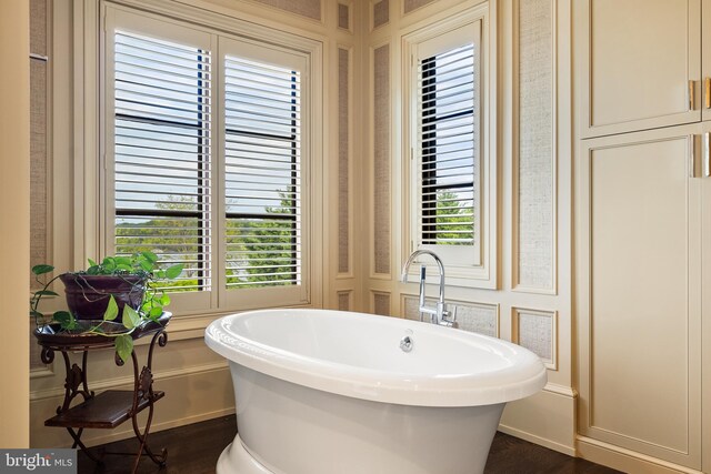 bathroom featuring baseboards, a freestanding tub, and wood finished floors
