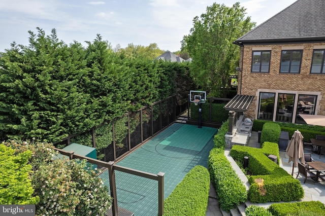 view of basketball court featuring fence and basketball hoop