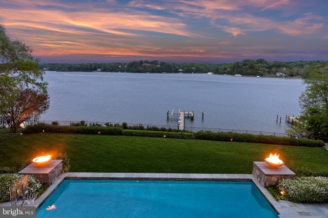 view of swimming pool featuring a lawn, a water view, and a fenced in pool