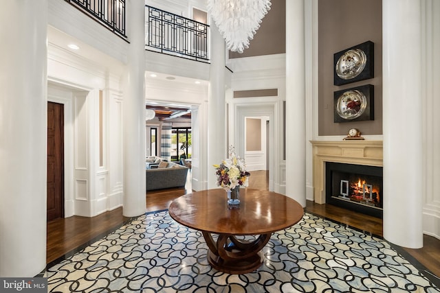 foyer with a glass covered fireplace, wood finished floors, and a towering ceiling
