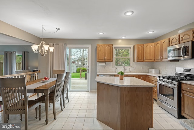 kitchen featuring a kitchen island, appliances with stainless steel finishes, a wealth of natural light, and a notable chandelier