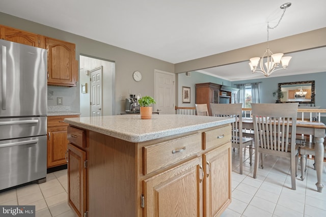 kitchen featuring light tile patterned flooring, freestanding refrigerator, an inviting chandelier, pendant lighting, and a kitchen island