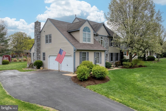 view of front facade with driveway, a chimney, an attached garage, a shingled roof, and a front yard