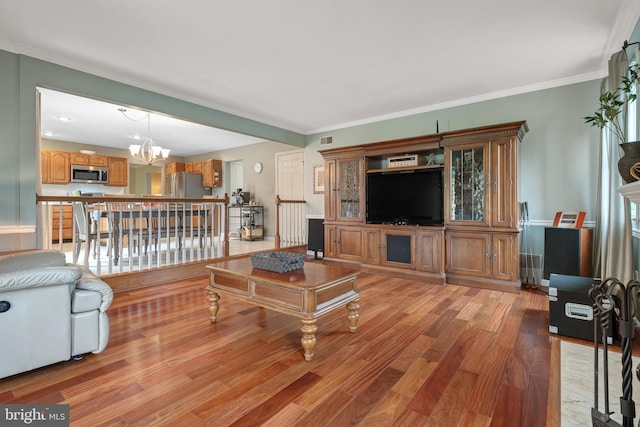 living area featuring ornamental molding, a chandelier, light wood finished floors, and visible vents