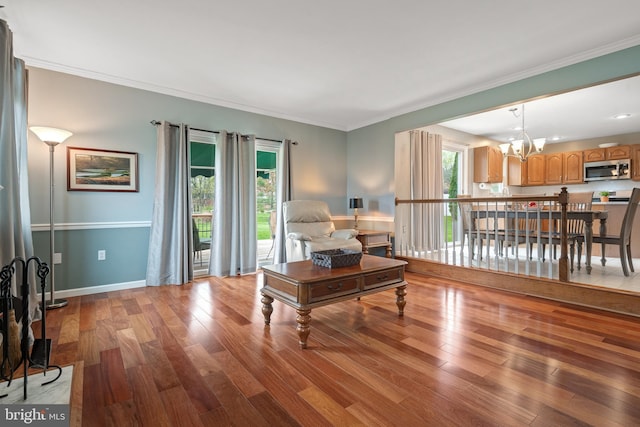 living room featuring a chandelier, wood finished floors, baseboards, and ornamental molding