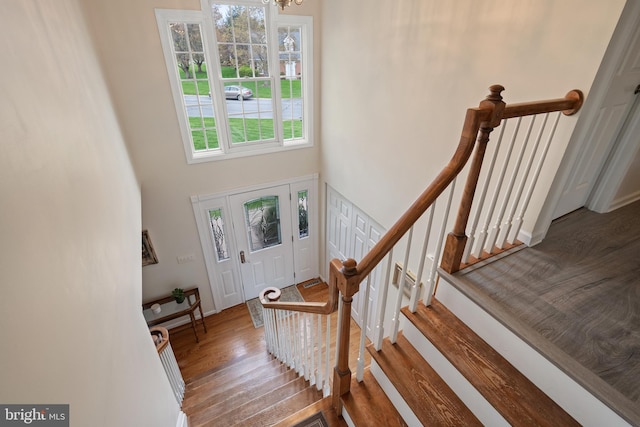 entryway featuring baseboards, a high ceiling, wood finished floors, and an inviting chandelier