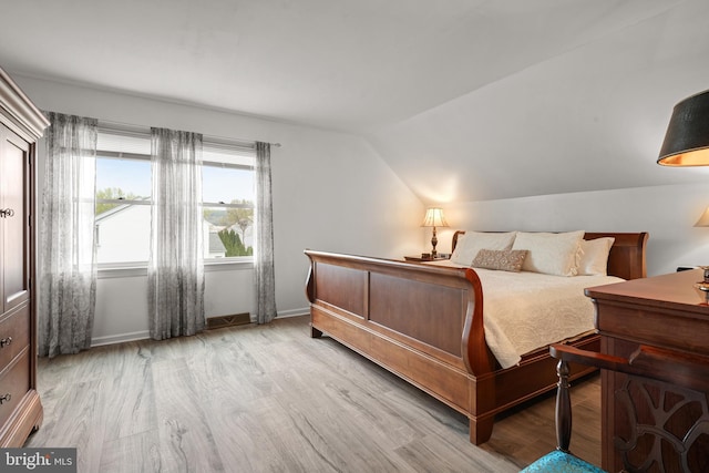 bedroom featuring vaulted ceiling, baseboards, and light wood-style floors