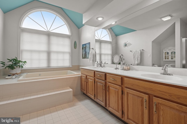 bathroom with tile patterned floors, vaulted ceiling, a healthy amount of sunlight, a sink, and a garden tub