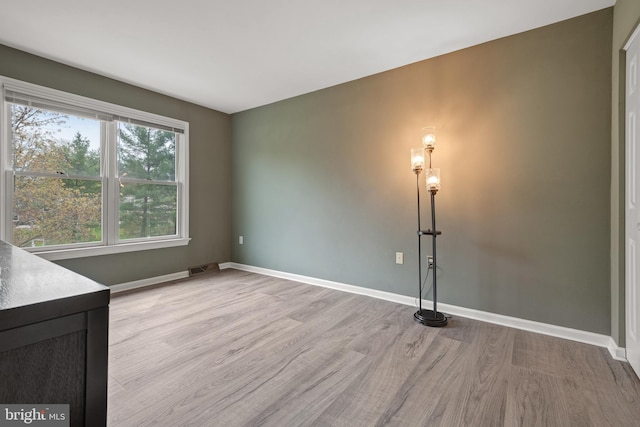 unfurnished room with light wood-type flooring, visible vents, and baseboards