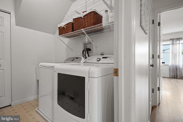 clothes washing area featuring washing machine and clothes dryer, baseboards, light floors, and laundry area