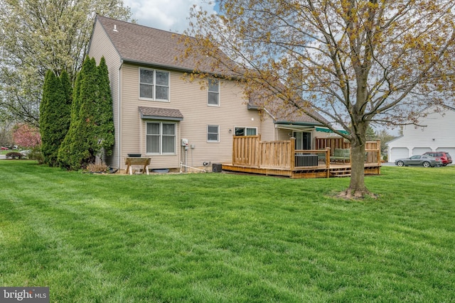 rear view of property with a wooden deck, a lawn, and roof with shingles