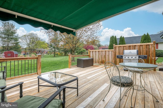 deck featuring grilling area, a lawn, and an outbuilding