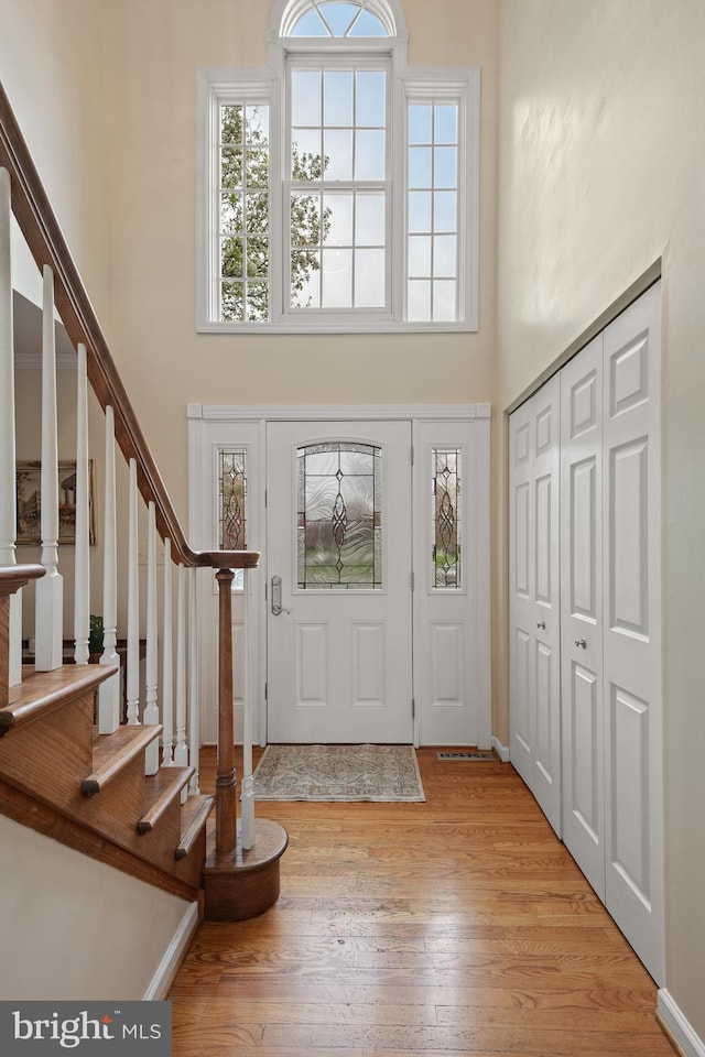 foyer entrance featuring a high ceiling, hardwood / wood-style flooring, and stairs