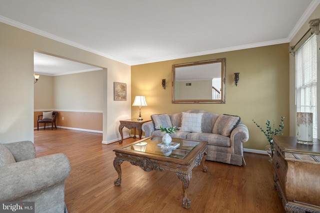living area featuring baseboards, wood finished floors, and ornamental molding