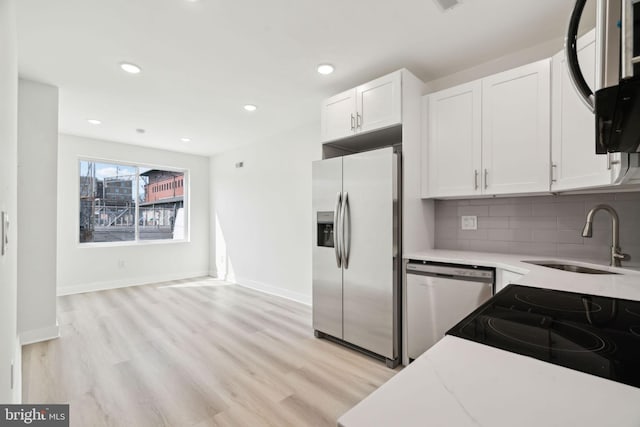 kitchen featuring a sink, tasteful backsplash, stainless steel fridge, dishwashing machine, and white cabinets