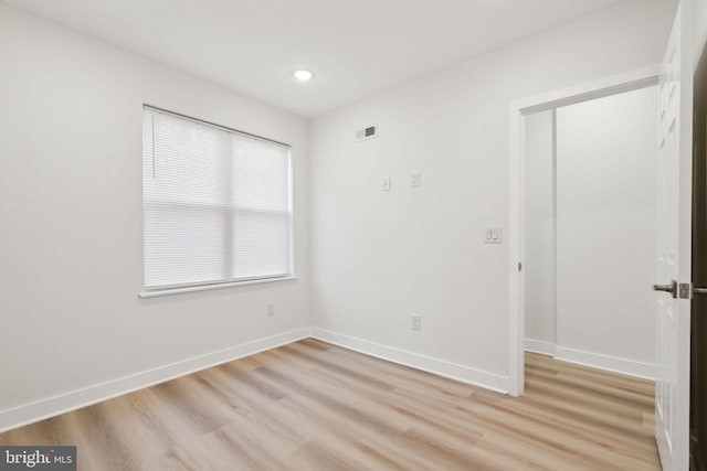 unfurnished room featuring baseboards, light wood-style floors, and visible vents