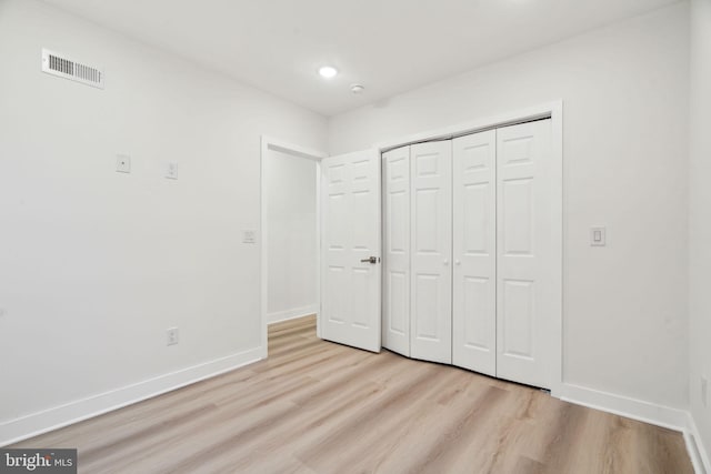 unfurnished bedroom featuring light wood-style flooring, a closet, baseboards, and visible vents