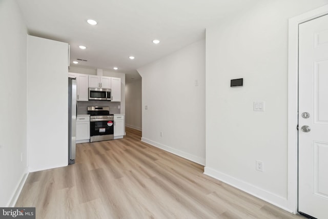 kitchen featuring recessed lighting, backsplash, light wood-style floors, white cabinets, and appliances with stainless steel finishes