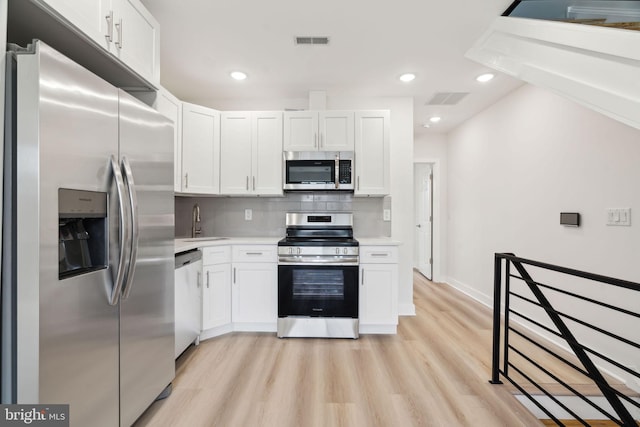 kitchen with light countertops, tasteful backsplash, visible vents, white cabinets, and appliances with stainless steel finishes