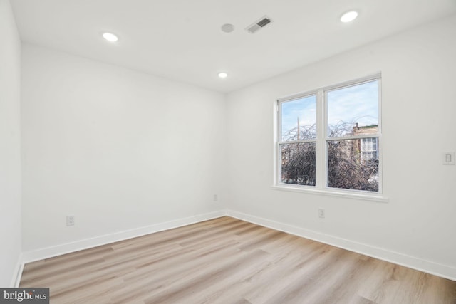 empty room with baseboards, visible vents, and light wood finished floors