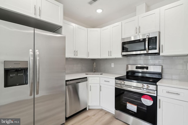 kitchen featuring light countertops, a sink, white cabinetry, appliances with stainless steel finishes, and decorative backsplash
