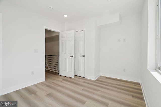 unfurnished bedroom with baseboards, a closet, wood finished floors, and recessed lighting