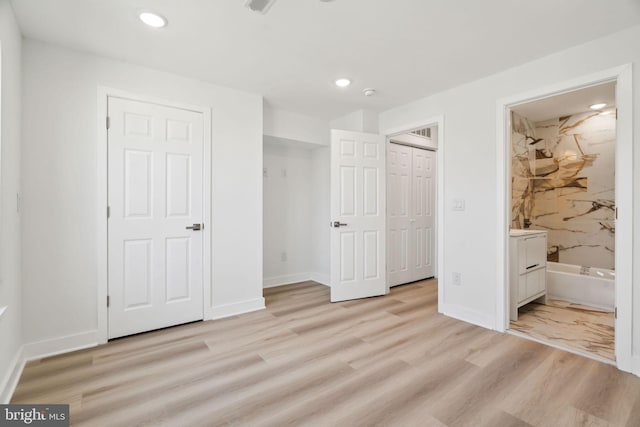 unfurnished bedroom featuring baseboards, ensuite bath, recessed lighting, and light wood-type flooring