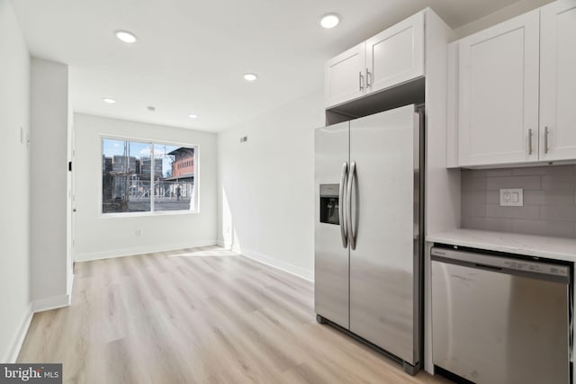kitchen with light wood finished floors, tasteful backsplash, appliances with stainless steel finishes, white cabinets, and recessed lighting