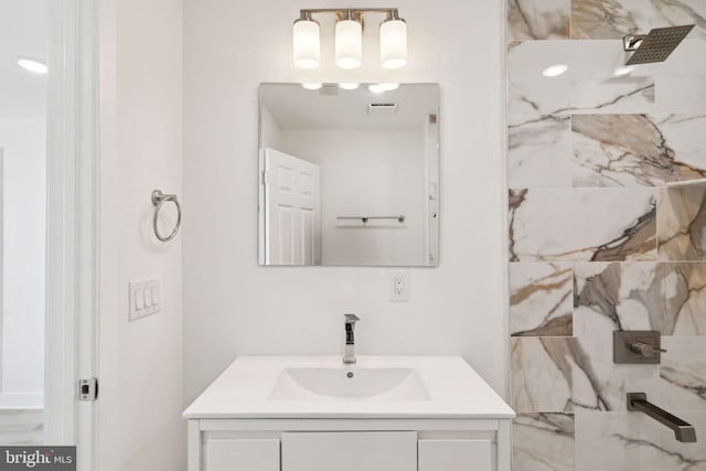 bathroom with vanity and a marble finish shower
