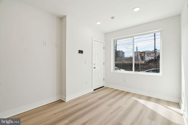 empty room featuring baseboards, light wood-style floors, and recessed lighting