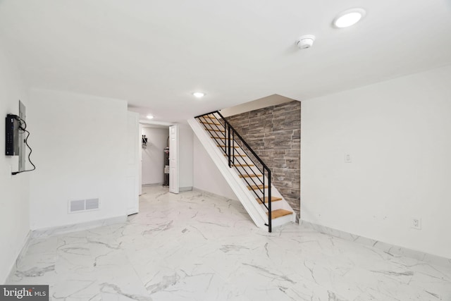interior space with marble finish floor, baseboards, visible vents, and stairway
