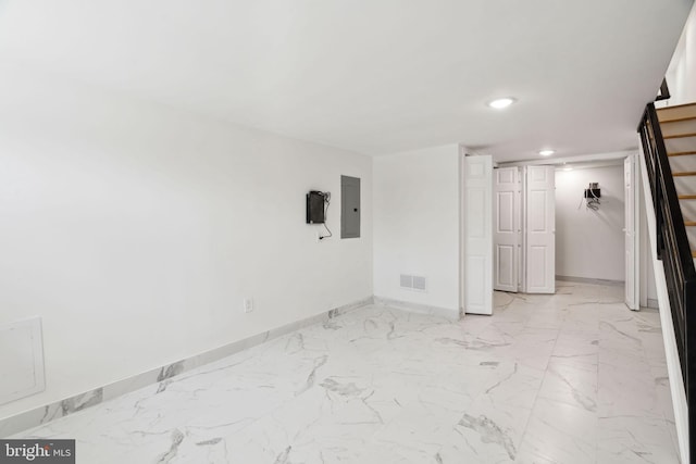 unfurnished room with electric panel, stairway, marble finish floor, baseboards, and visible vents
