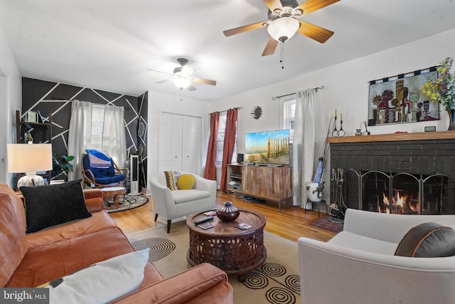 living area with ceiling fan, wood finished floors, and a brick fireplace