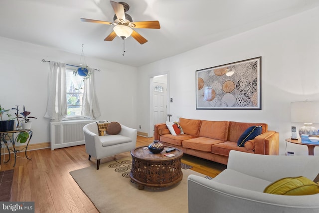 living room featuring hardwood / wood-style floors, ceiling fan, baseboards, and radiator