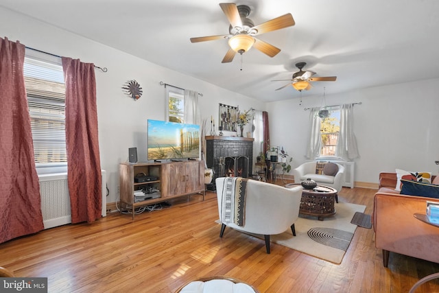 living area with baseboards, wood finished floors, and a ceiling fan