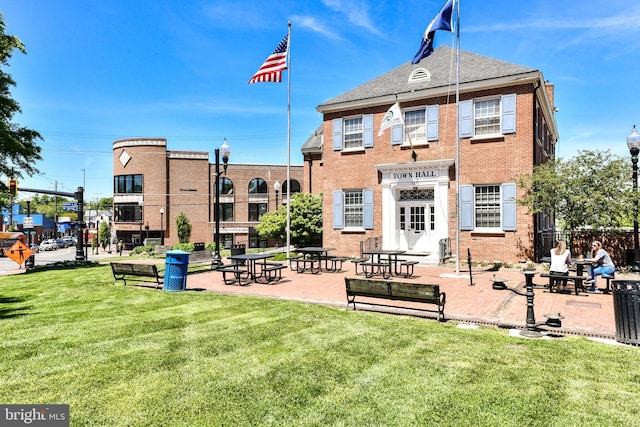 rear view of property featuring brick siding, fence, and a yard
