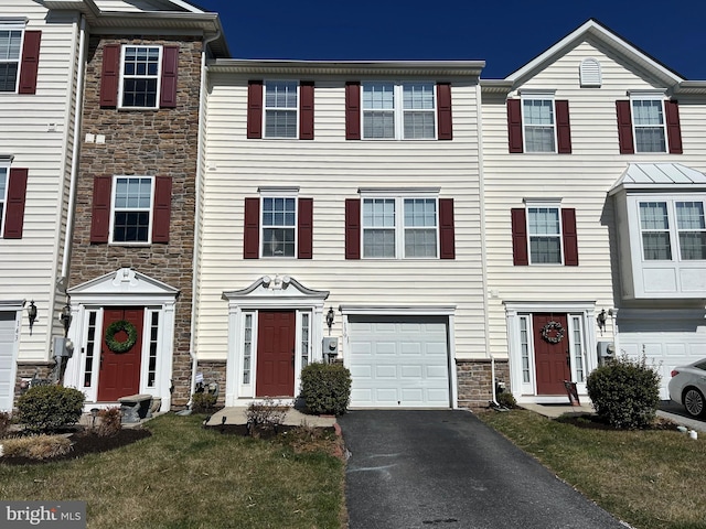 multi unit property featuring aphalt driveway, stone siding, and a garage