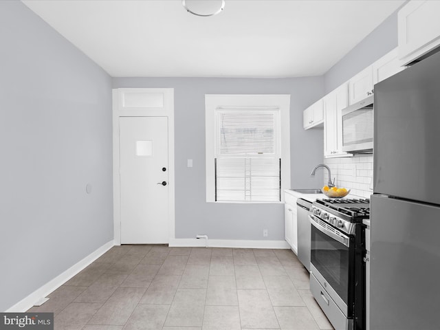 kitchen with decorative backsplash, white cabinets, light countertops, appliances with stainless steel finishes, and a sink